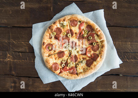 Top view of fresh delicious pizza on white napkins on wooden table Stock Photo