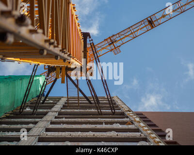 Yellow crane attached to building under construction Stock Photo