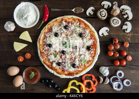 top view of italian pizza with various ingredients on wooden tabletop Stock Photo