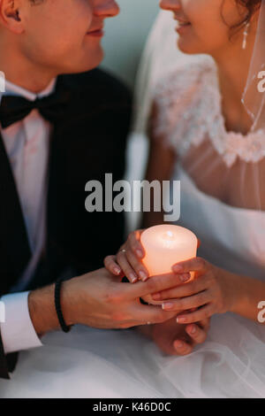 The shining candle in the hands of the newlyweds. Stock Photo