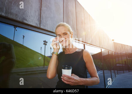 Happy businesswoman talking on the mobile and holding cup of coffee. Stock Photo