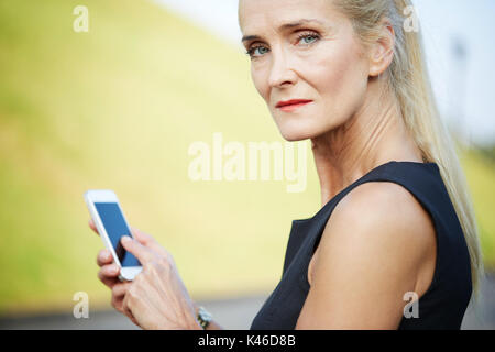 Close up portrait of mature serious woman using mobile. Stock Photo