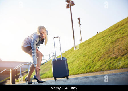 Businesswoman suffering from leg sore on business trip. Stock Photo