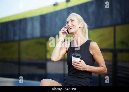 Portrait of businesswoman having break with coffee and talking on mobile. Stock Photo