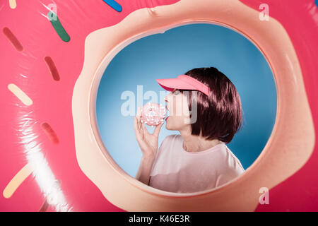 stylish woman eating sweet doughnut into swimming tube Stock Photo