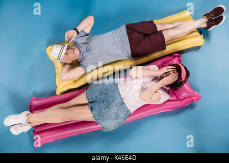 stylish elderly couple lying on colorful swimming mattresses Stock Photo