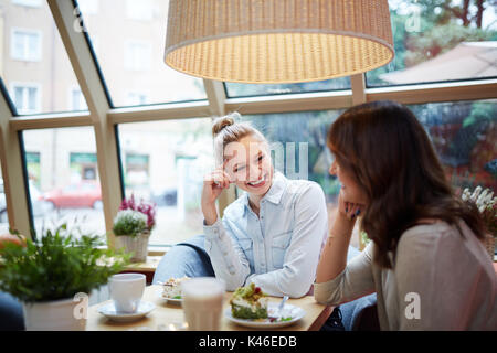 Portrait of young women having nice conversation at cafe. Stock Photo
