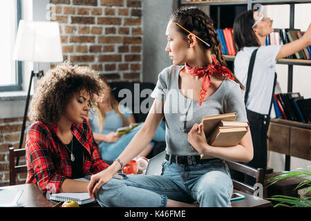 pensive multiethnic women working while sitting at table in home office Stock Photo