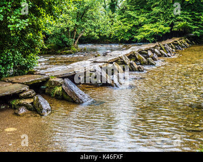A rainy day at Tarr Steps, the famous 17-span medival clapper bridge across the River Barle in Exmoor, Somerset. Stock Photo