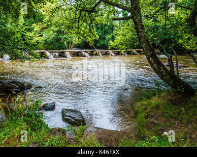 A rainy day at Tarr Steps, the famous 17-span medival clapper bridge across the River Barle in Exmoor, Somerset. Stock Photo