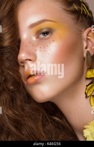 Portrait of beautiful red-haired girl with brightly colored art makeup and curls. Beauty face. Stock Photo