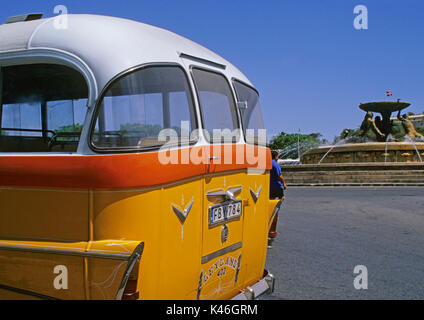 Yellow Leyland Bus and Triton Fountain in the City Gate Square of Valletta, Malta Stock Photo