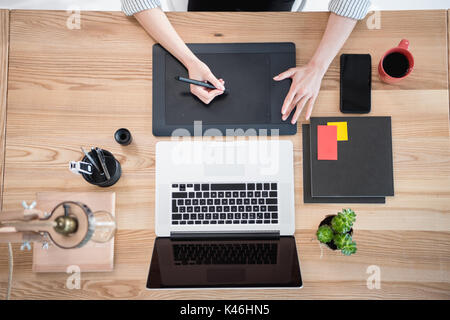 cropped shot of woman working with drawing tablet and laptop on tabletop Stock Photo
