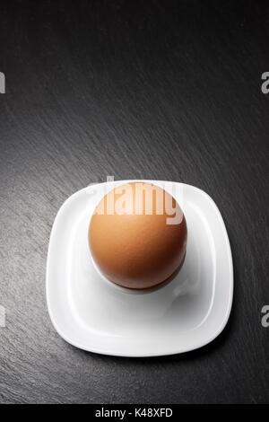 Closeup of a brown egg on a table slate. Stock Photo