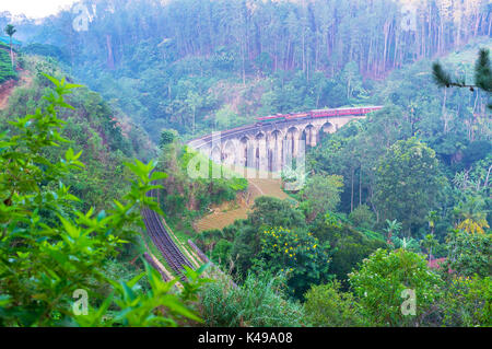 The train runs along the Nine Arches Bridge, seen through the jungle, gadens and farms, from the mountain slope, located in valley, Demodara, Ella, Sr Stock Photo