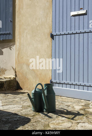 Two old fashioned watering cans taking a well earned break after watering the lovely gardens of a quaint French hilltop property on a warm Autumn day Stock Photo