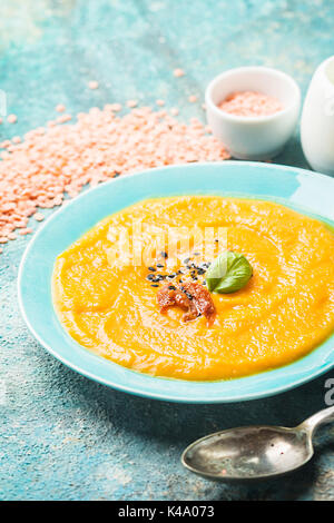 Red lentil soup in blue plate over blue stone backgroud