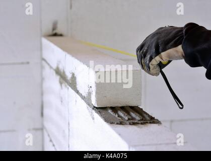 The bricklayer measures a newly built wall with a tape measure. Stock Photo
