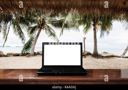 Computer laptop on wooden table, at the beach in summer. Clipping path empty white screen Stock Photo
