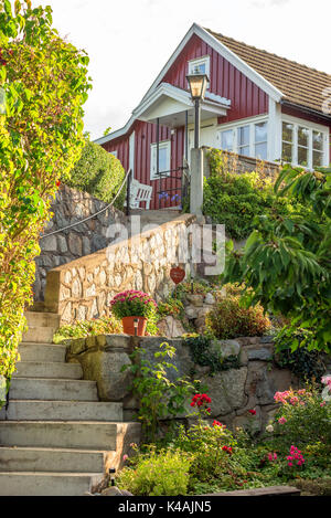 Karlskrona, Sweden - August 28, 2017: Travel documentary of the city. Garden stairway leading up to red and white cottage. Flowers on rocks and lamppo Stock Photo