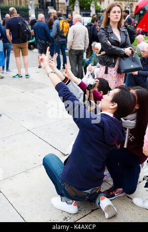 London, UK. Asian tourists stop to take a selfie in Parliament Square. Stock Photo