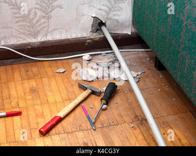 PVC pipe, a hole in concrete wall and work tools spread out the floor Stock Photo