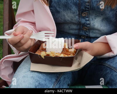 Young girl holds a waffle bought in the park which is topped with a giant marshmallow purchased from Fortnum and Mason in Piccadilly, London UK. Stock Photo