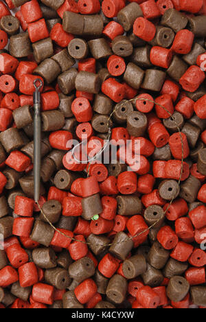 Fishing bait with hook and brown with red pre-drilled halibut pellets for carp fishing  background Stock Photo