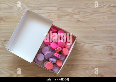 Carton paper present box with colorful macaroons cakes on wooden floor Stock Photo
