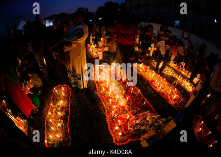 Family members light candles and put them on the graves of their loved ones during All Souls' Day on November 02 at Holy Rosary Catholic Church in Dha Stock Photo