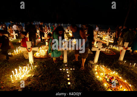 Family members light candles and put them on the graves of their loved ones during All Souls' Day on November 02 at Holy Rosary Catholic Church in Dha Stock Photo