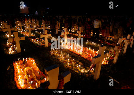 Family members light candles and put them on the graves of their loved ones during All Souls' Day on November 02 at Holy Rosary Catholic Church in Dha Stock Photo