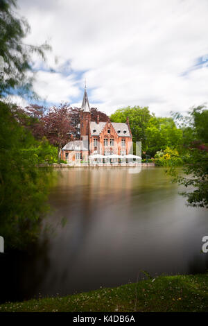 The romantic lake Minnewater with its famous house with towers in the south of Bruges, Belgium. Long exposure shot. Stock Photo