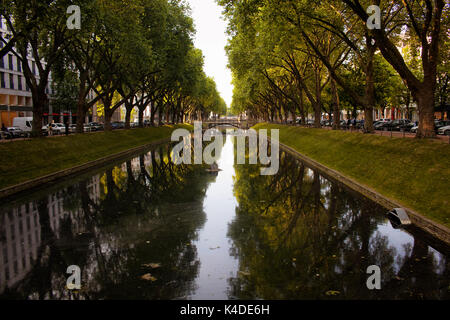 Famous and beautiful tourist attraction of Dusseldorf: Konigsallee. It's an urban boulevard by big trees and close end water way. Stock Photo