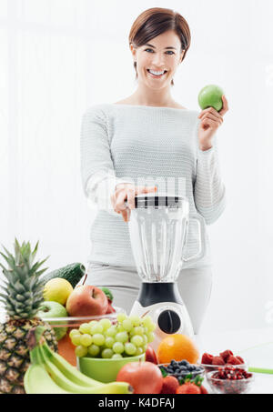 Smiling confident woman using a blender and preparing nutrient detox drinks, healthy eating and diet concept Stock Photo