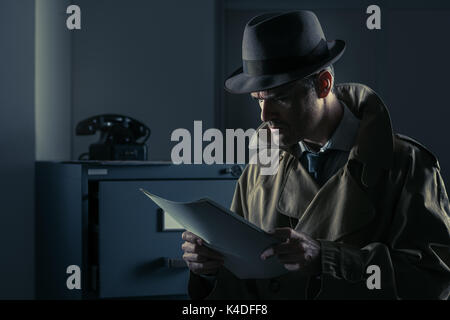 Vintage undercover agent stealing files in a corporate office late at night, security and data theft concept Stock Photo