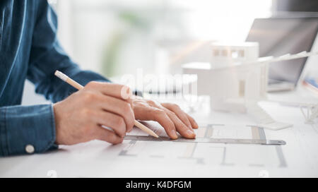 Professional architect working at office desk, he is drawing and making measurements on a project blueprint, engineering and architecture concept Stock Photo