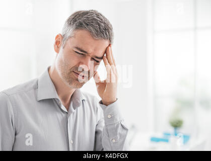 Stressed tired man having a bad headache, he is touching his temples Stock Photo