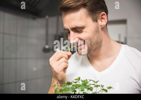 Close up portrait of chef in the kitchen smelling lemon balm Stock Photo