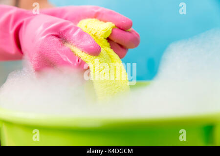 Close-up of cleaner woman hand squeezing cloth in bucket filled with soap Stock Photo