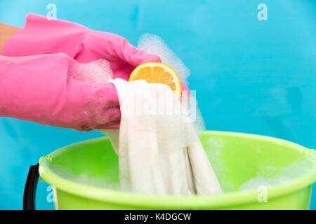 Close-up of cleaner woman hand removing stain from white cloth with lemon Stock Photo