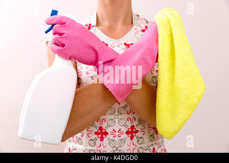 Portrait of woman holding in her hand a spray bottle and a microfiber cloth while standing at isolated background. Stock Photo