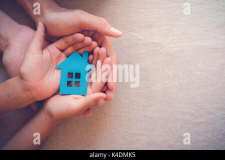 Adult and child hands holding paper house, family home and real estate concept Stock Photo