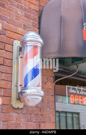 Classic electric spiral barber pole outside a local barber shop. Stock Photo