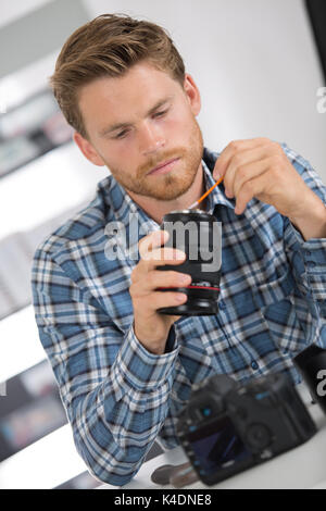 man cleaning lens of his digital camera with special brush Stock Photo
