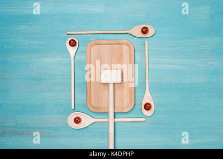 Top view of wooden cutting board, meat hammer and spoons with cherry tomatoes on table Stock Photo