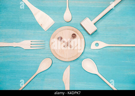 top view of various wooden kitchen utensils with clock symbol on plate
