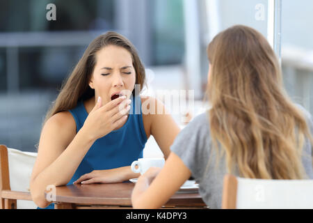 Bored friend having a conversation sitting in a coffee shop outdoors Stock Photo