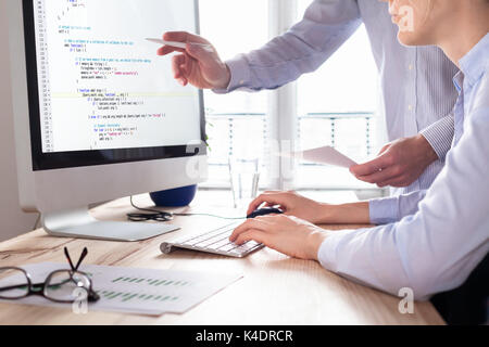 Team of web app developers coding website source code and debugging on computer screen before deployment Stock Photo