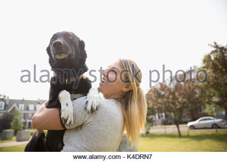Female pet owner holding dog in park